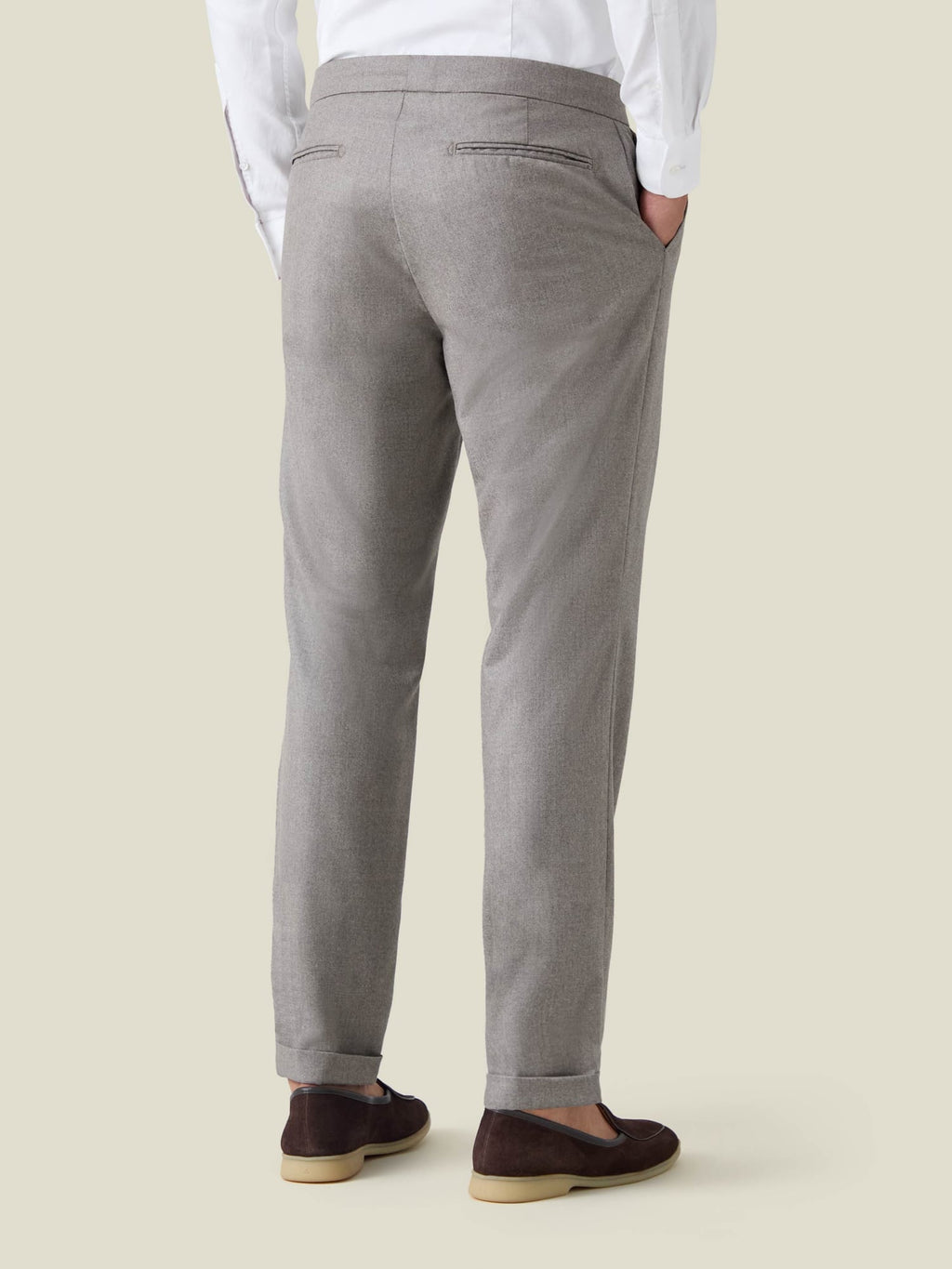 Rear view of a man wearing the Camel Beige Wool Pleated Trousers, showcasing the tapered fit and cuffed hems.
