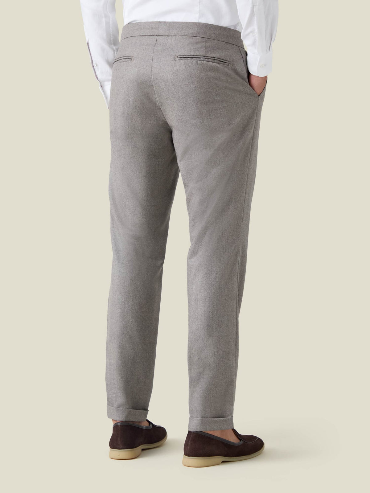 Rear view of a man wearing the Camel Beige Wool Pleated Trousers, showcasing the tapered fit and cuffed hems.