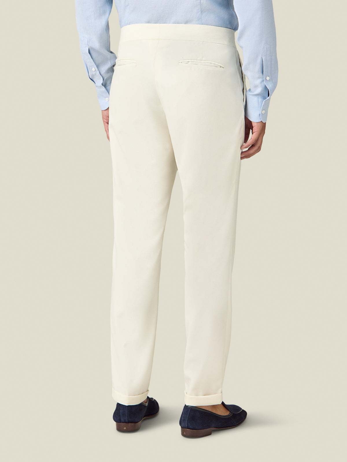 Back view of a model wearing the Luca Faloni Wool Pleated Trousers in ivory, styled with a light blue shirt.