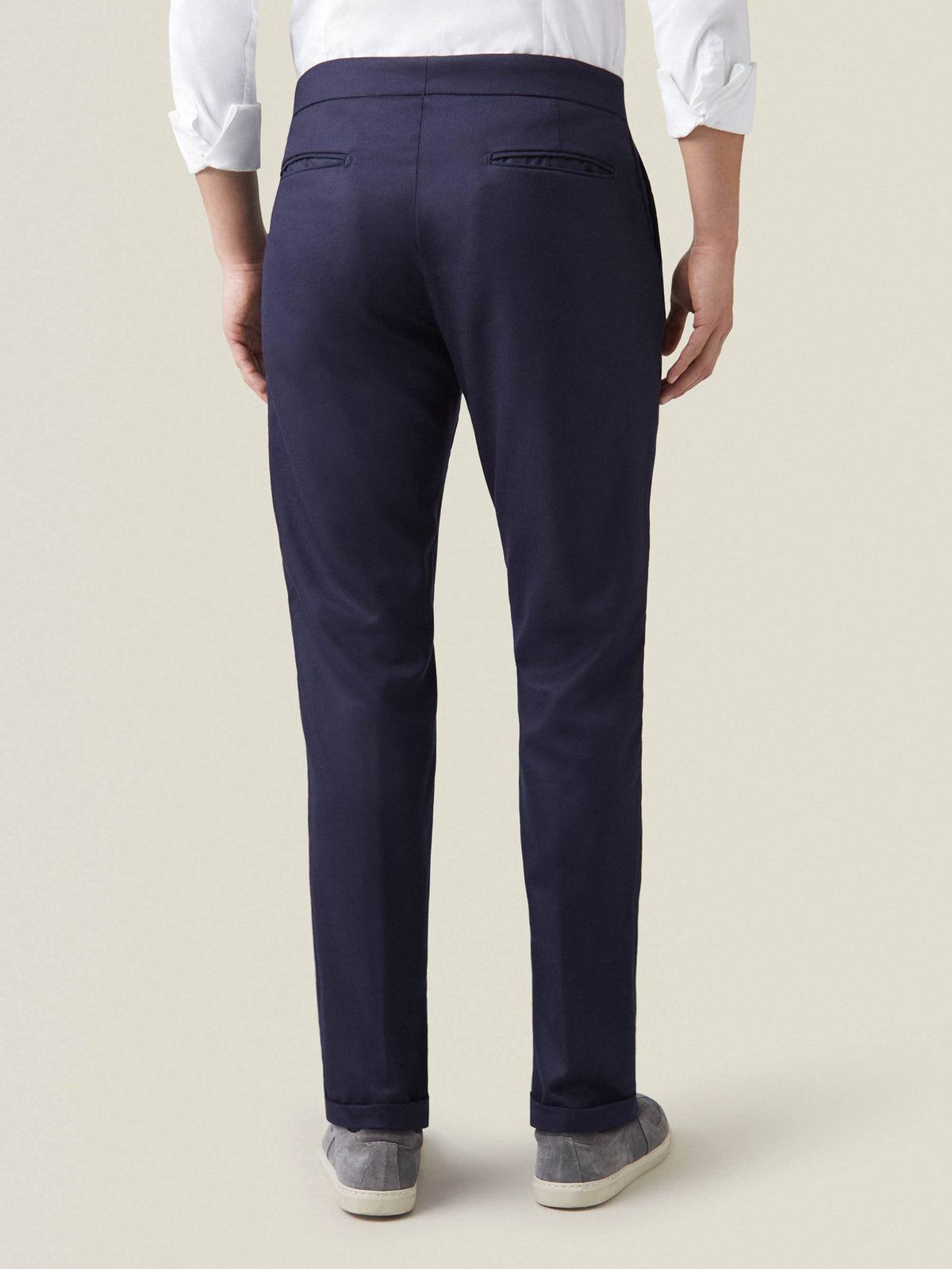 Back view of a model wearing the Midnight Blue Wool Pleated Trousers, showcasing their slim tapered fit and cuffed hems.