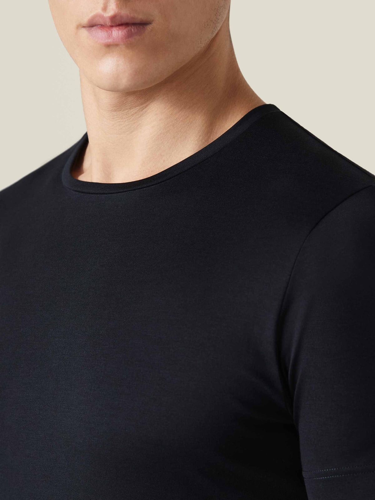 Detailed close-up of a model wearing the black Silk-Cotton T-Shirt, showcasing the classic crew neckline and smooth fabric.