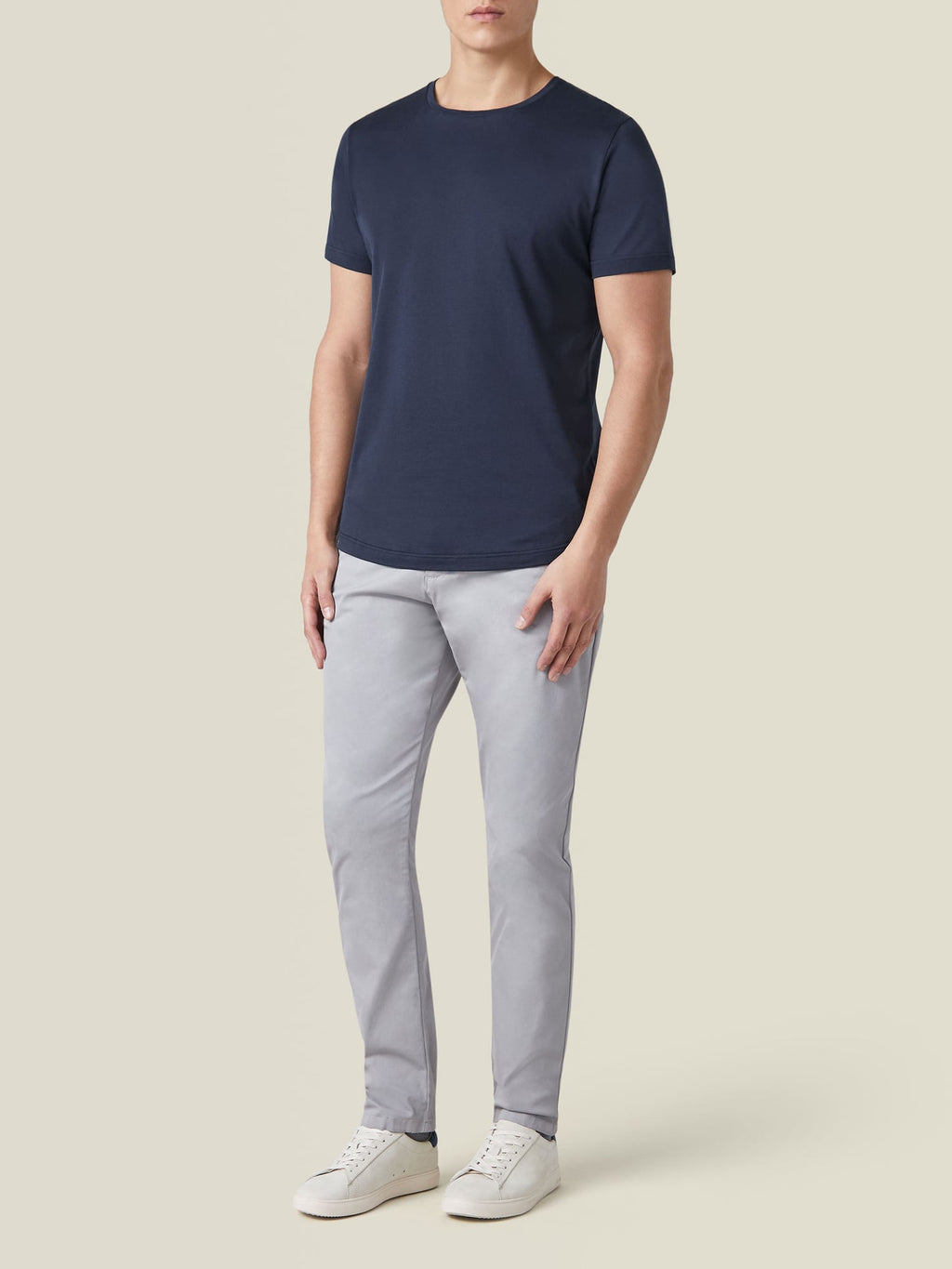 Front-three-quarter view of a model wearing the Silk-Cotton T-Shirt in Midnight Blue with grey trousers and white sneakers.