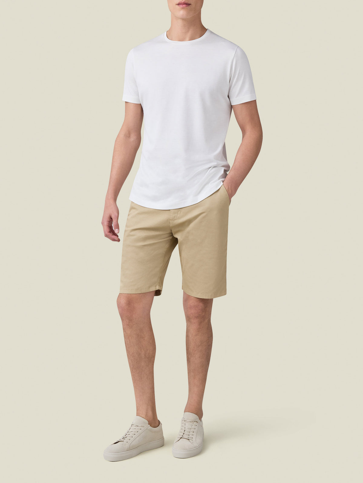 Model wearing Luca Faloni's white Silk-Cotton T-Shirt with beige shorts and white sneakers against a neutral background.