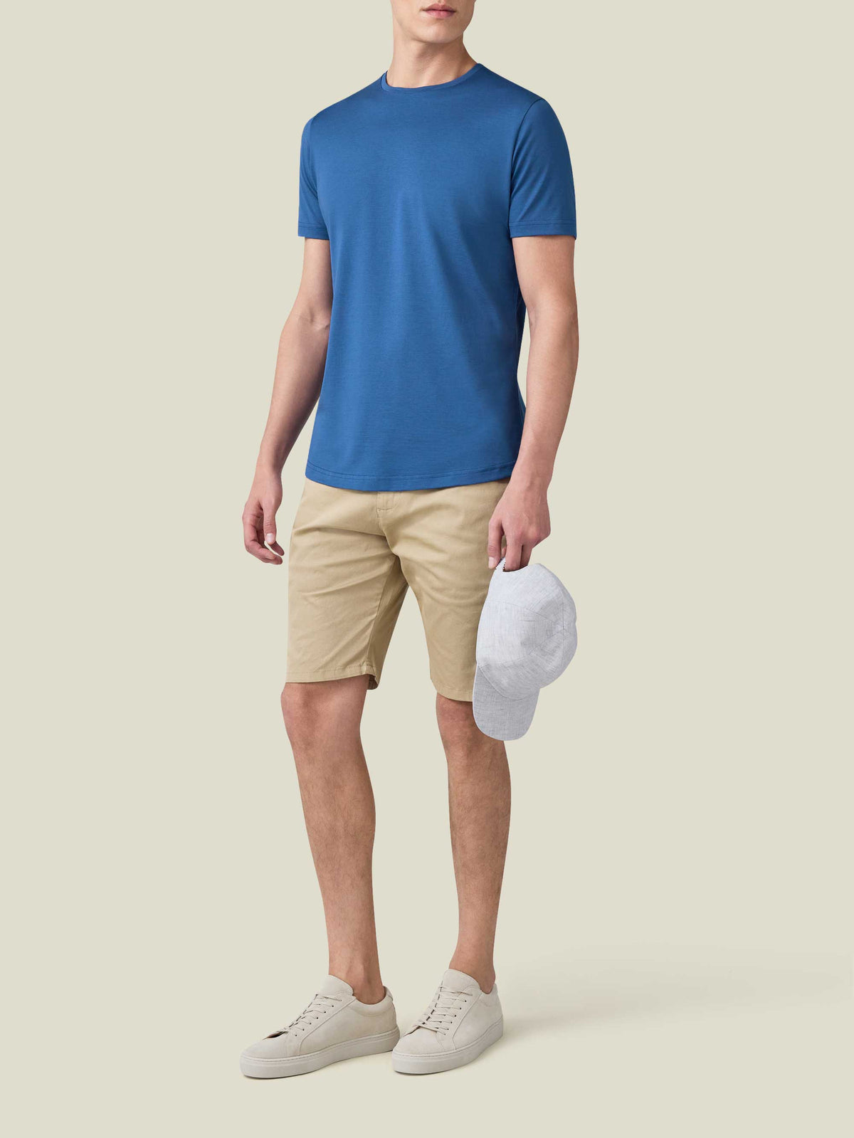 Full-length shot of a model wearing the royal blue Silk-Cotton T-Shirt with beige shorts and light sneakers.