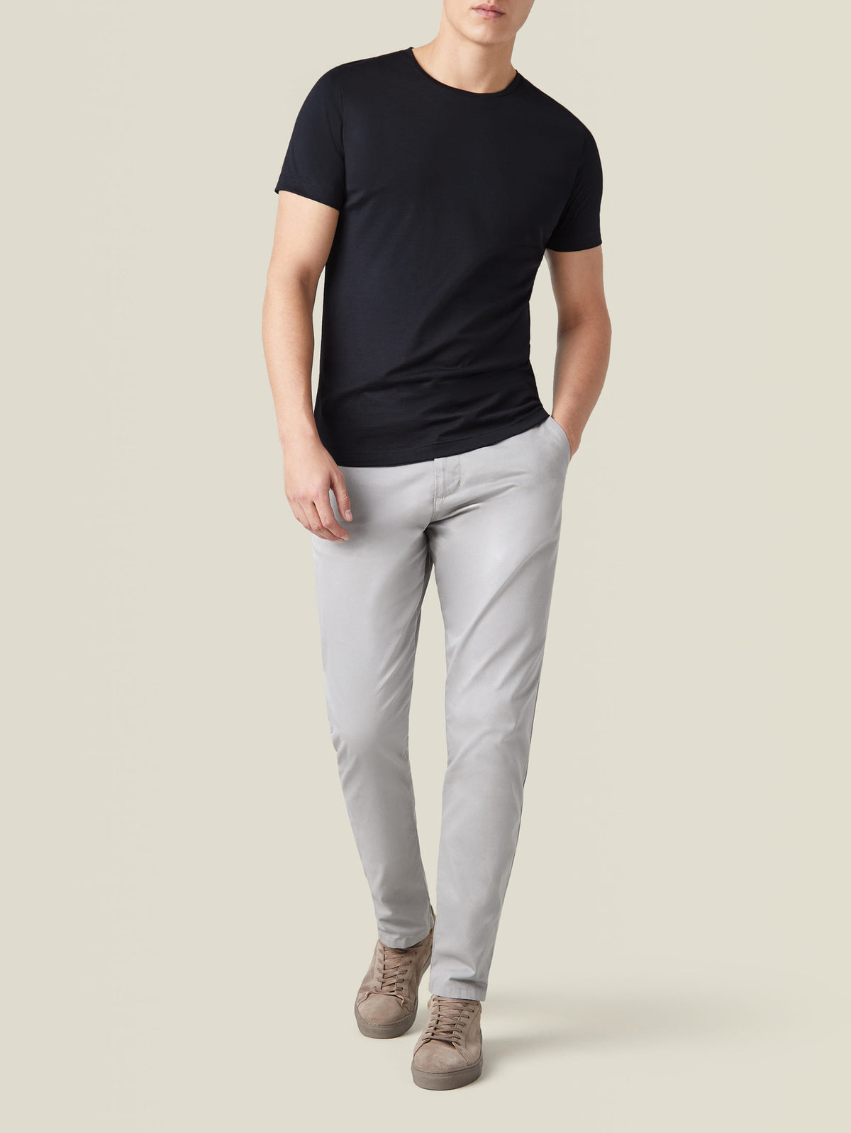 Model wearing the Black Silk-Cotton T-Shirt paired with light grey trousers and taupe sneakers, showcasing the full outfit.