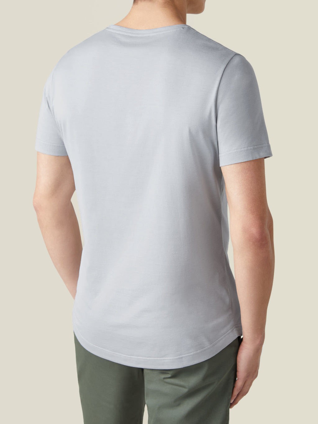 Back view of a model wearing a light grey silk-cotton t-shirt, showcasing its classic fit and curved hem.