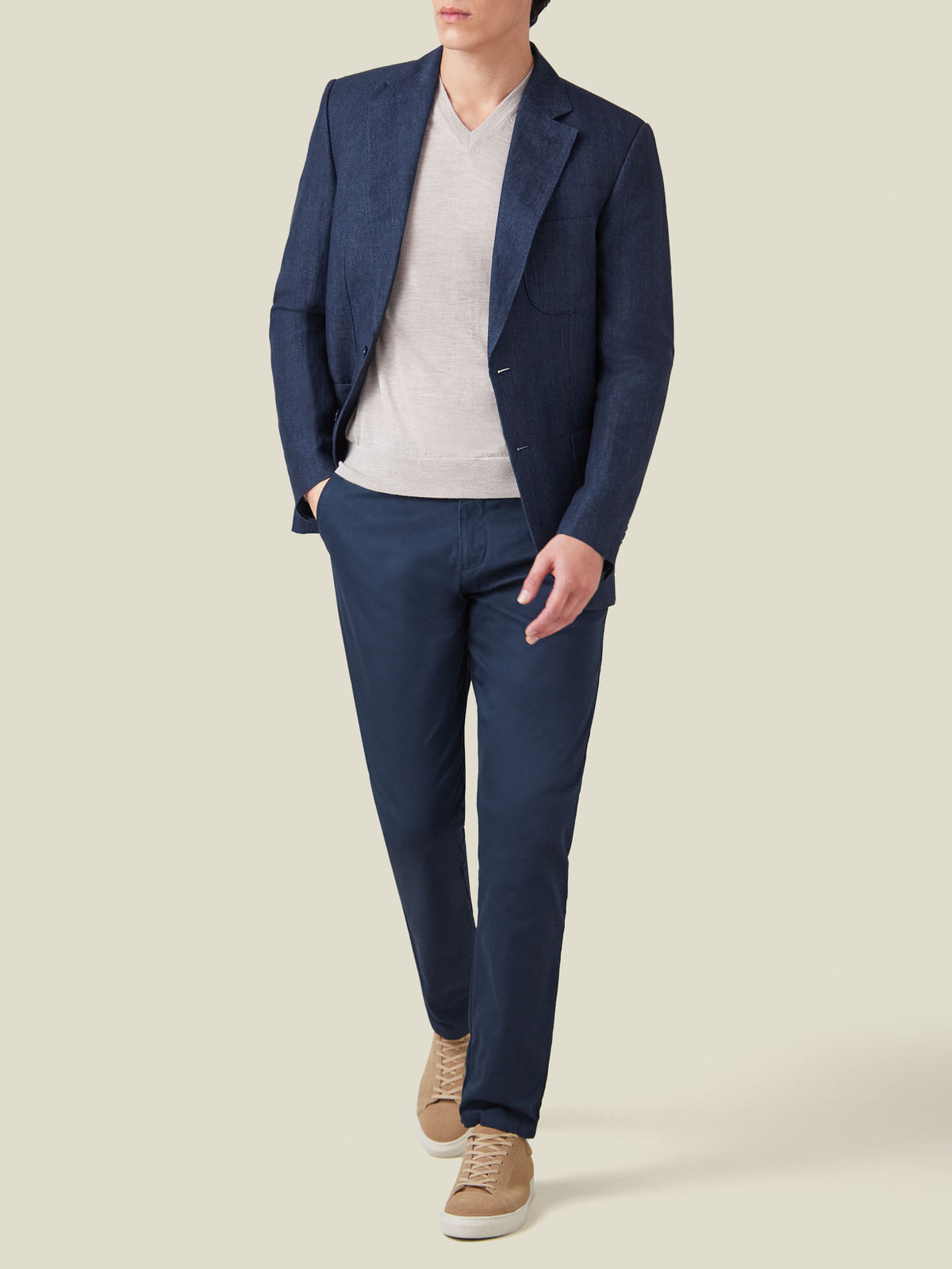 A model wears the Luca Faloni Oatmeal Silk-Cashmere V-neck sweater layered under a blue blazer and paired with navy trousers.
