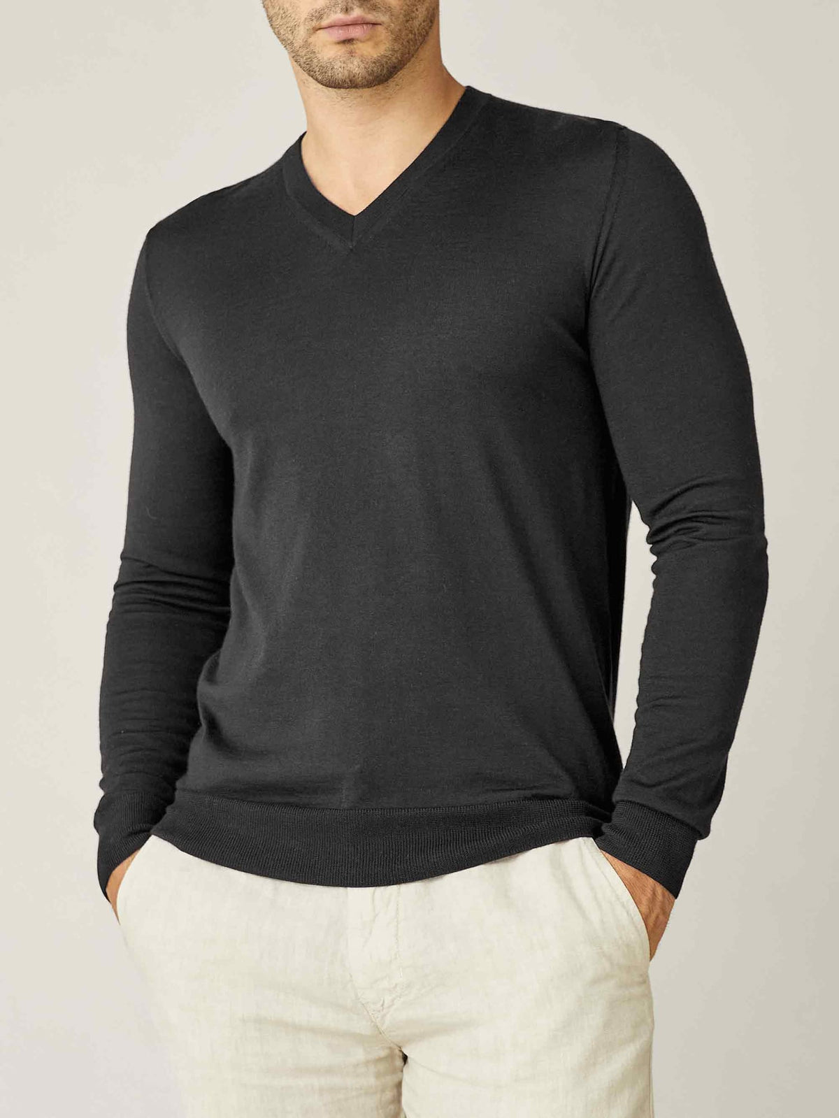 Front view of a model wearing the Luca Faloni Silk-Cashmere V-Neck jumper in Charcoal Grey, paired with light trousers.