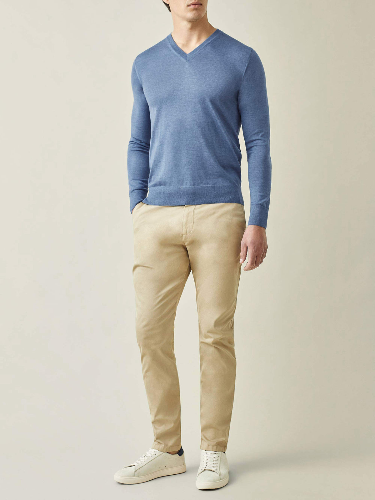 Front view of a model wearing the Luca Faloni Azure Blue Silk-Cashmere V-Neck with light beige chinos and white trainers.