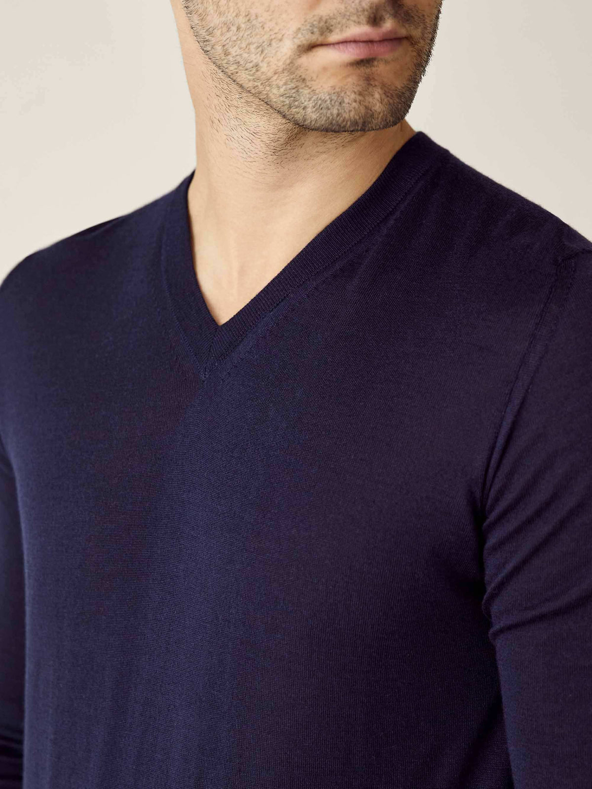 Close-up of a man wearing the navy blue silk-cashmere V-neck sweater, showing the detailed neckline.