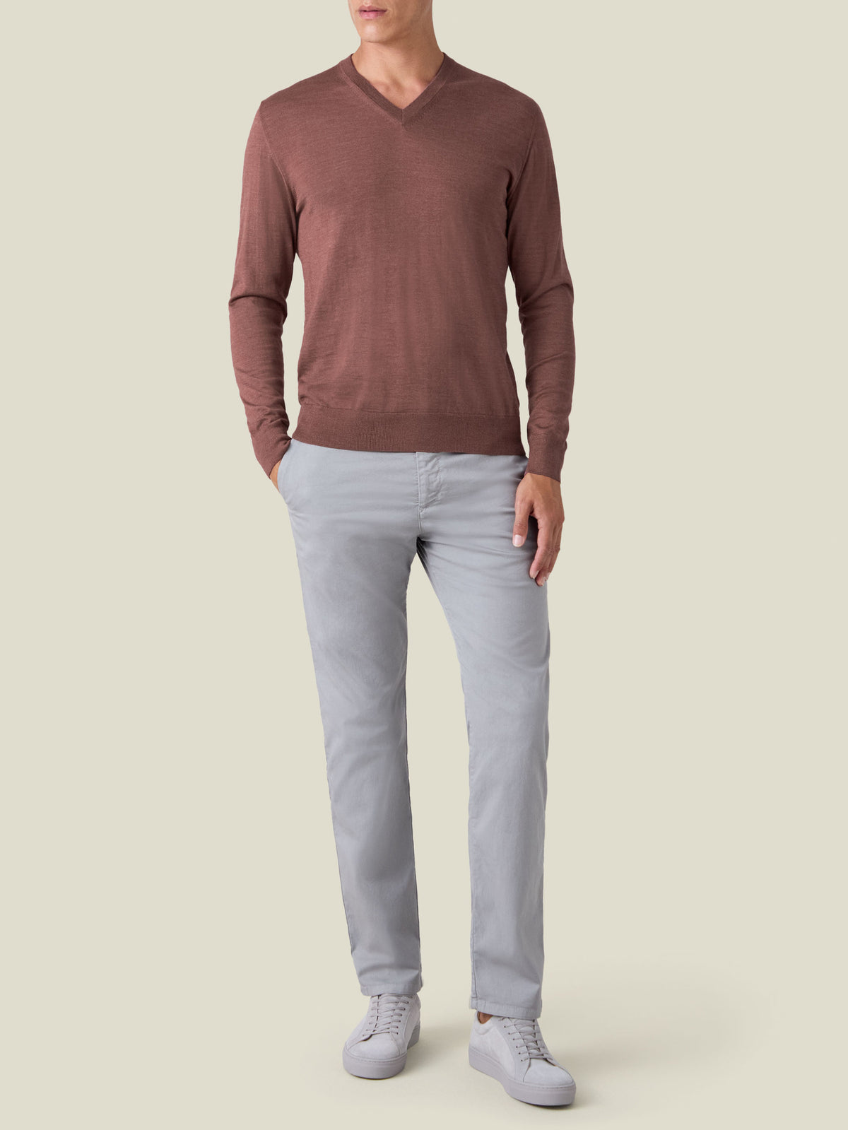 Full-length front view of a model wearing a Desert Rose silk-cashmere v-neck with light grey trousers and white sneakers.