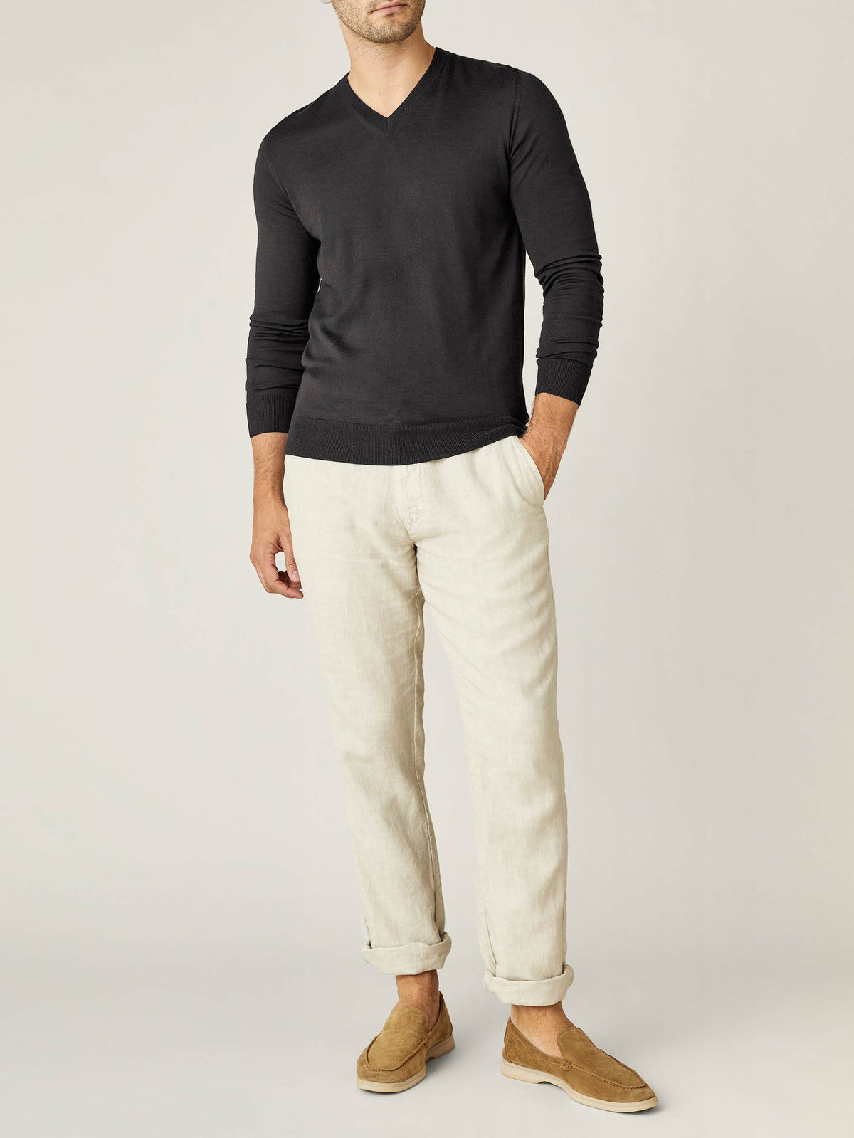 Full body view of a model wearing the Charcoal Grey Silk-Cashmere V-neck, paired with cream trousers and tan loafers.