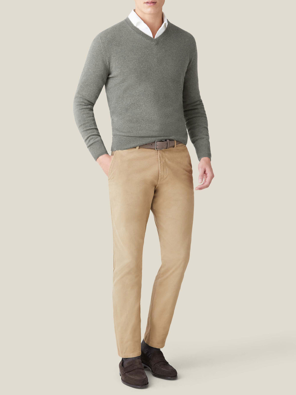 Model wears the Luca Faloni Moss Green Cashmere V Neck sweater layered over a white shirt and paired with tan trousers.