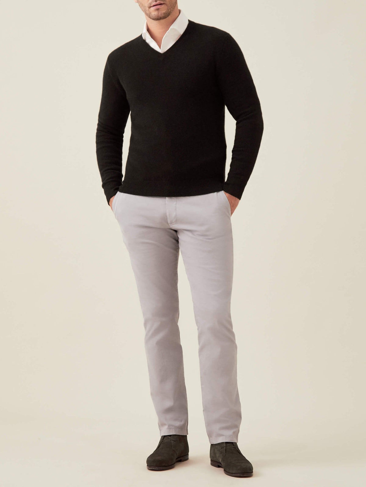 Full-length view of a man wearing the Luca Faloni black cashmere V-neck sweater with a white shirt and light grey trousers.
