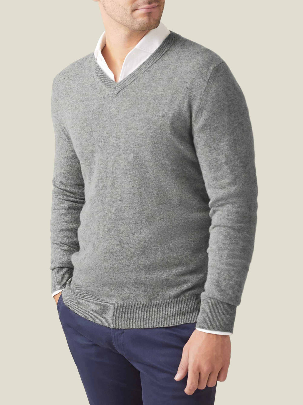 A man models the Dolomiti Grey cashmere V-neck sweater, layered over a white collared shirt and dark blue trousers.