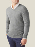 A man models the Dolomiti Grey cashmere V-neck sweater, layered over a white collared shirt and dark blue trousers.