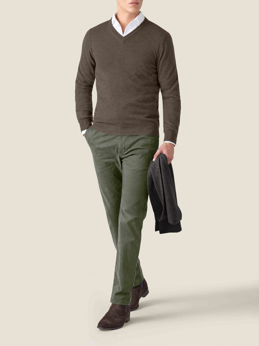 A man models a Luca Faloni chocolate brown cashmere v-neck sweater, layered over a white shirt and styled with green chinos.