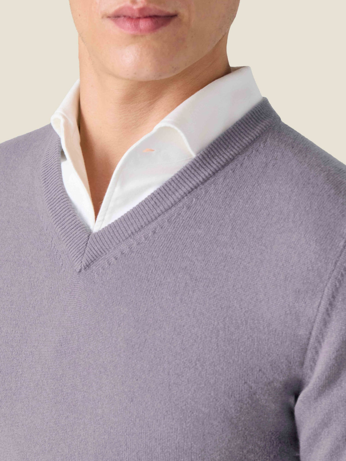 Close-up of a model wearing a violet cashmere V-neck sweater layered over a white collared shirt.