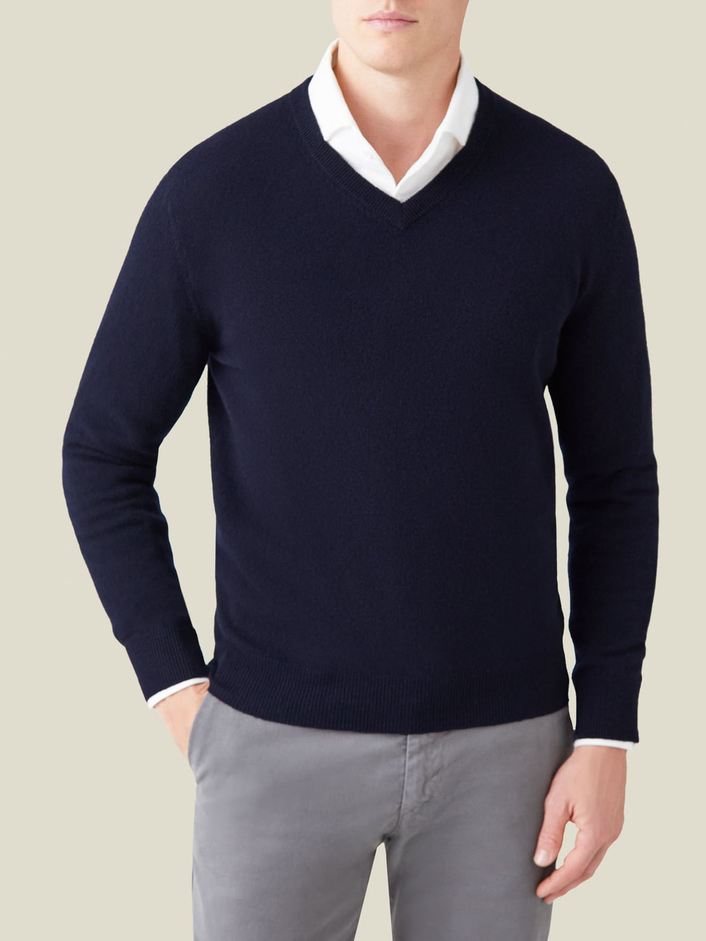 A model wears the Midnight Blue Cashmere V Neck from Luca Faloni, styled with a white shirt and grey trousers.