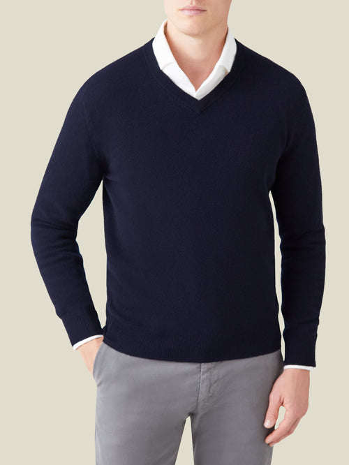 A model wears the Midnight Blue Cashmere V Neck from Luca Faloni, styled with a white shirt and grey trousers.