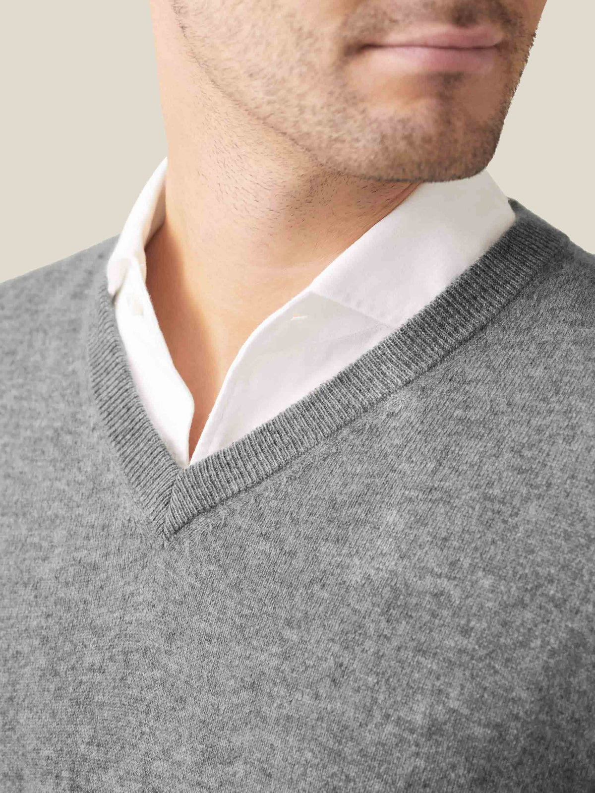 Close-up of the ribbed V-neckline of the Dolomiti Grey cashmere sweater, layered over a white collared shirt.