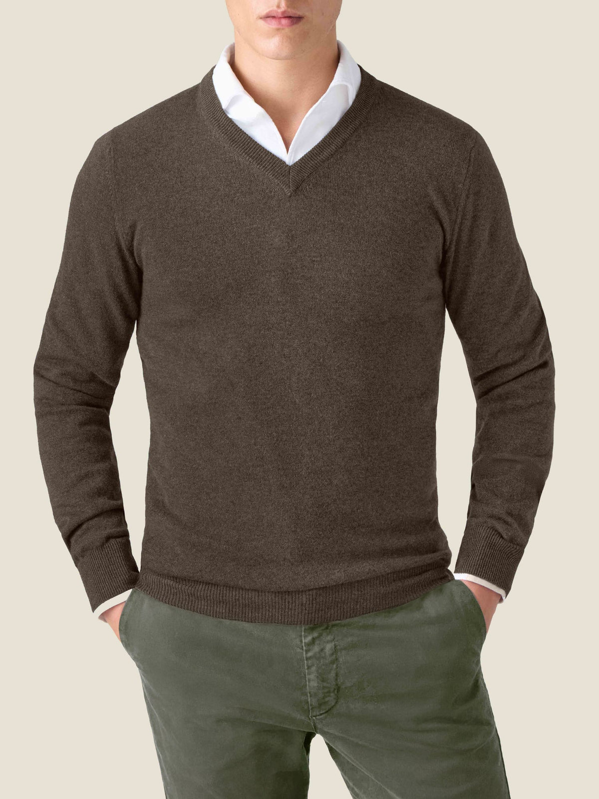 Front view of a model wearing the Chocolate Brown Cashmere V Neck Jumper, layered over a white shirt with green trousers.