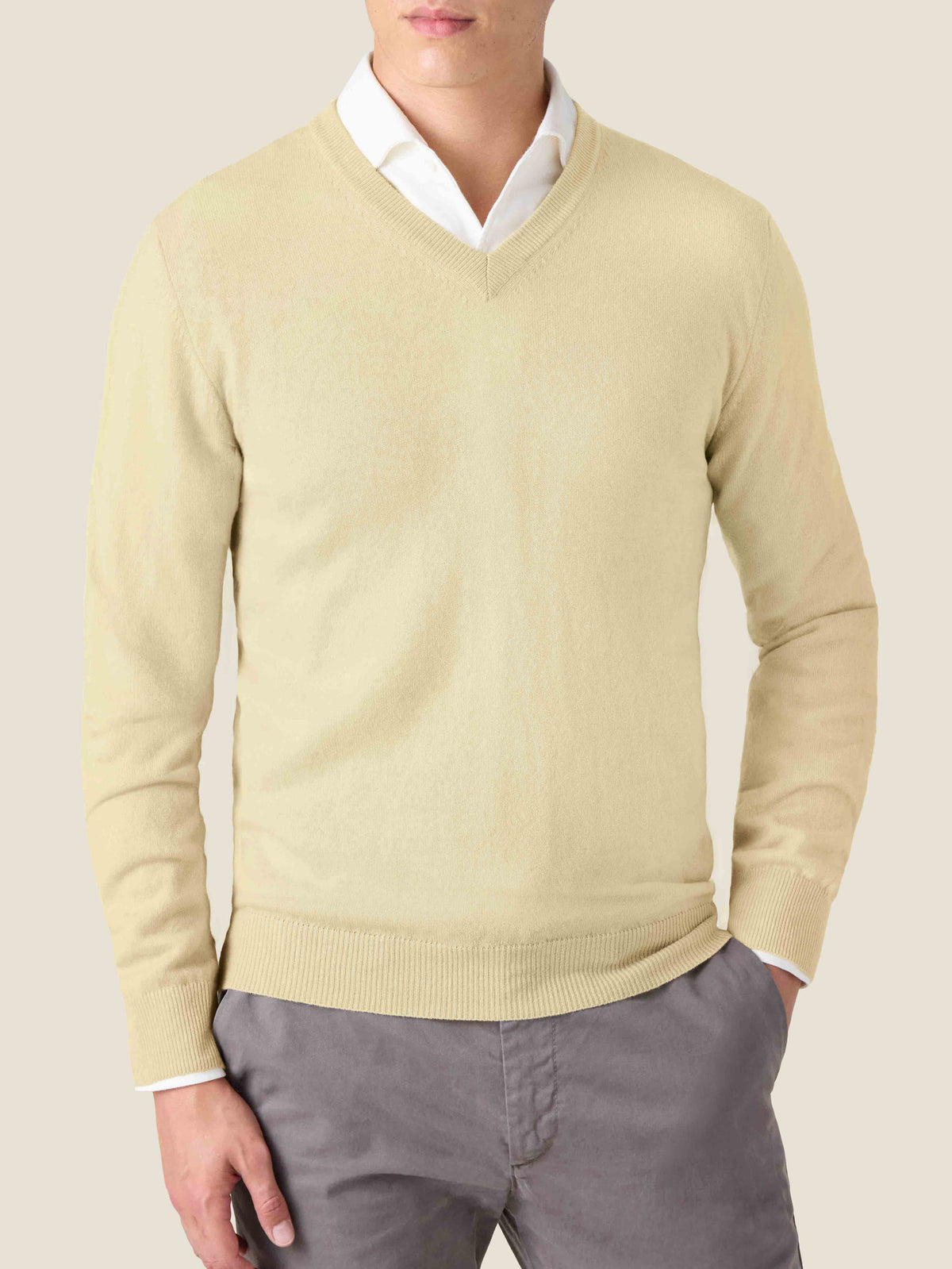 Luca Faloni's yellow pure cashmere V-neck sweater, shown on a model layered over a white shirt and paired with grey trousers.