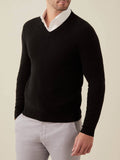 A model wears the Luca Faloni black cashmere V-neck sweater over a white shirt and light grey trousers.