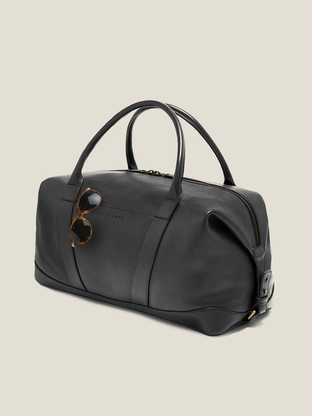 Side view of the Luca Faloni Weekender bag in black leather, with sunglasses tucked into the external sleeve pocket.