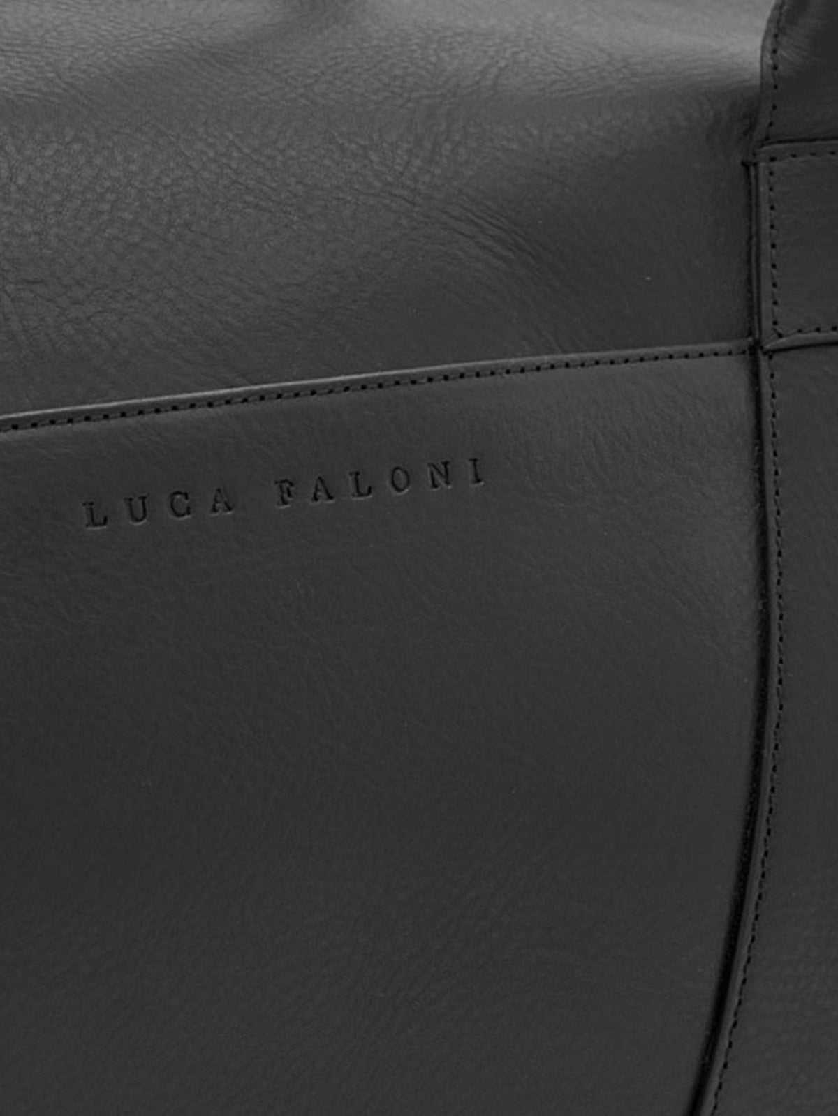 Close-up of the Luca Faloni embossed logo on the black full-grain leather Weekender bag.