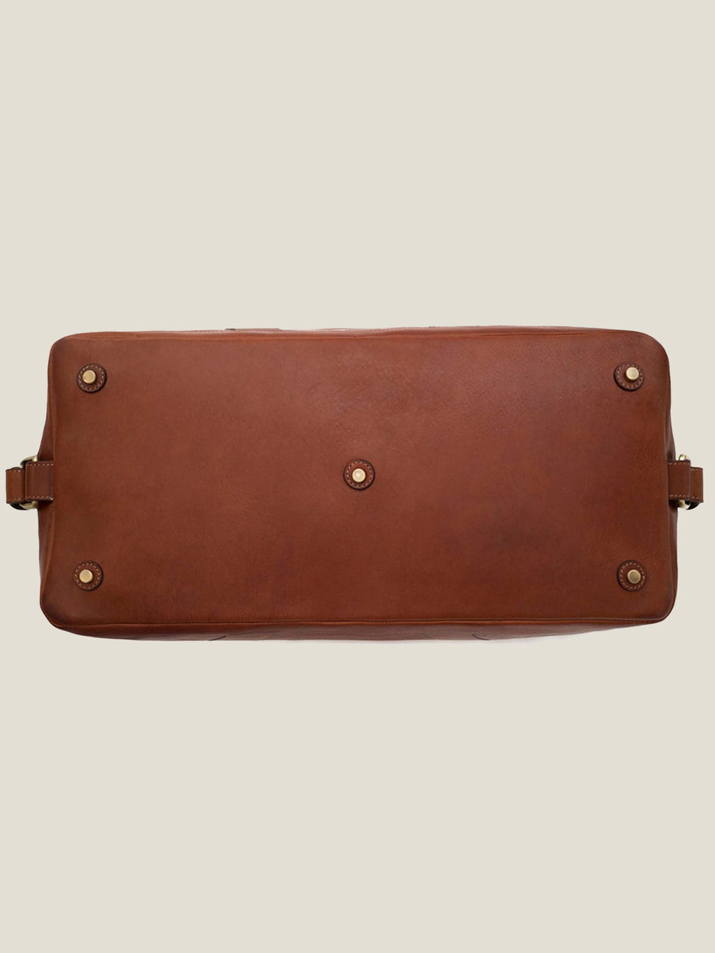 Underside of the caramel brown leather Weekender bag, showing the five protective metal studs on the base.