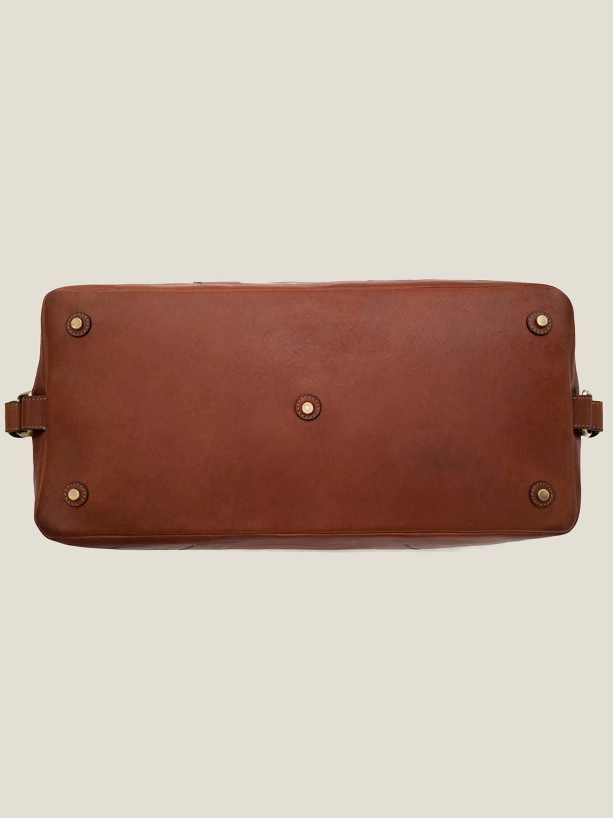 Underside of the caramel brown leather Weekender bag, showing the five protective metal studs on the base.