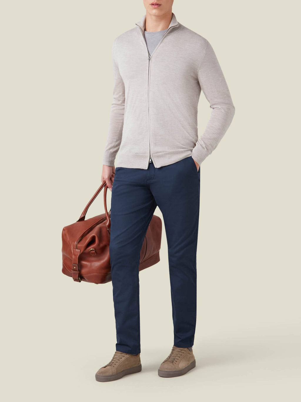 Front view of a model wearing the Oatmeal Silk-Cashmere Zip Cardigan with navy trousers, holding a brown leather bag.
