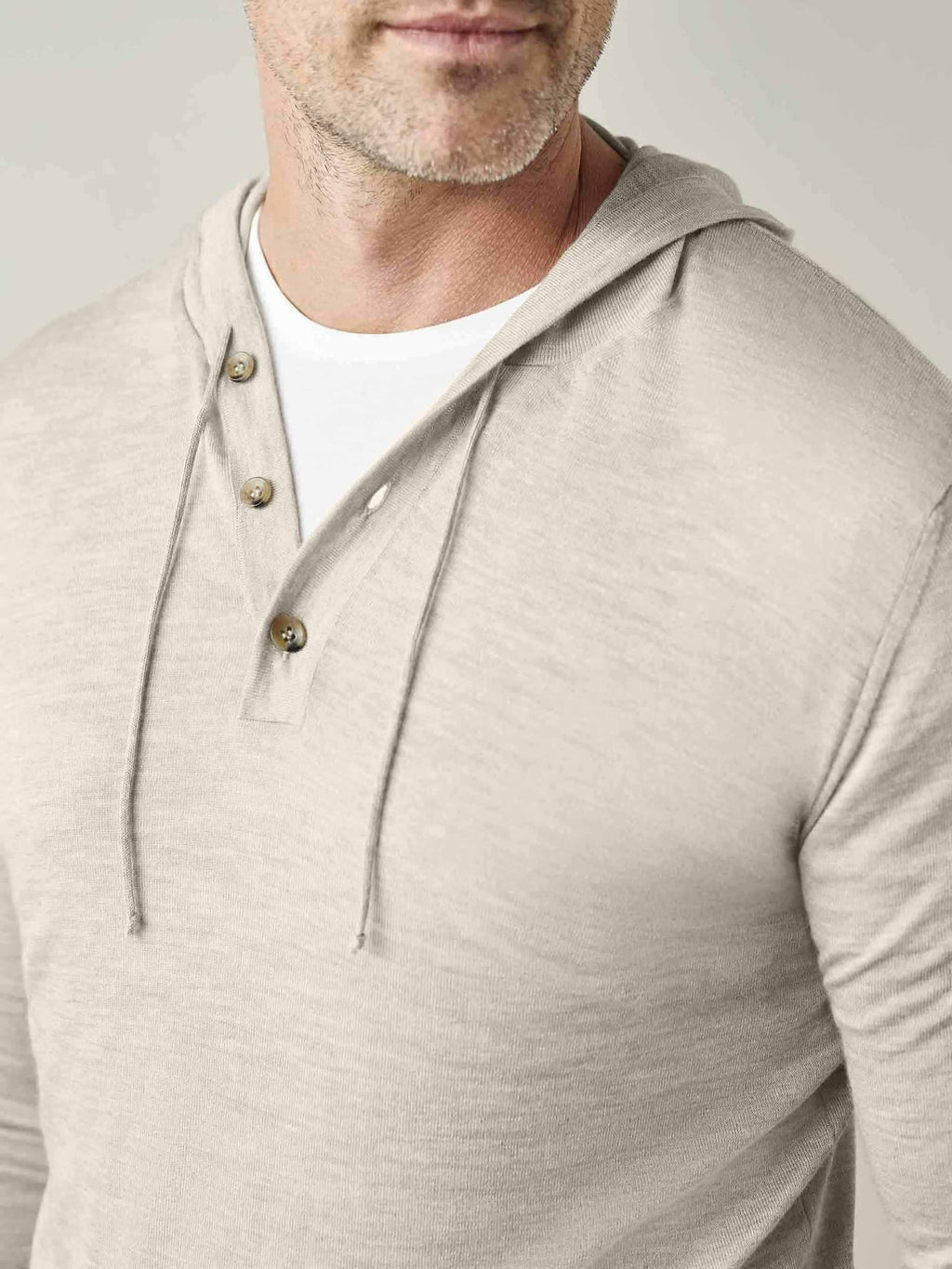 A close-up of a model wearing the Luca Faloni Silk-Cashmere Hoodie in Oatmeal, showing the button placket and drawstrings.