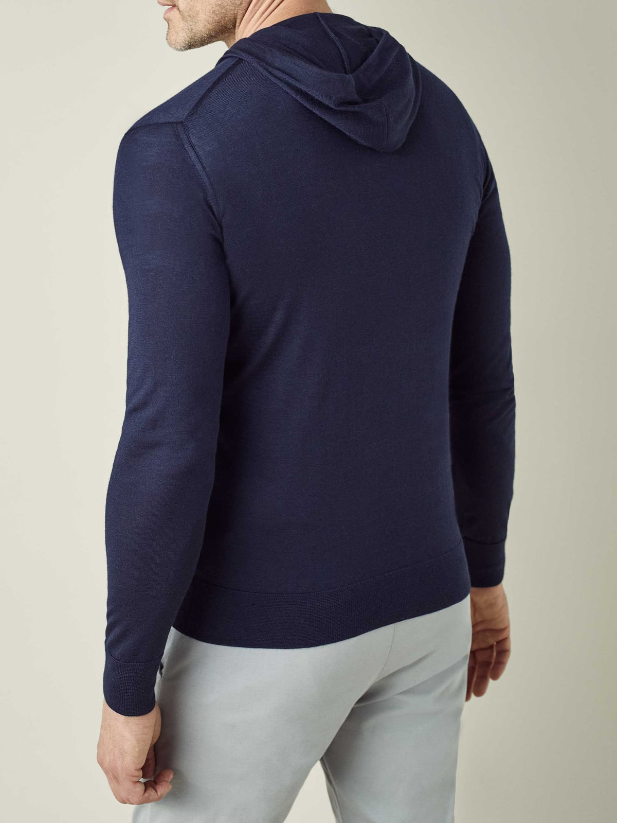 Back view of a model wearing the Luca Faloni Silk-Cashmere Hoodie in navy blue, highlighting its streamlined fit from behind.