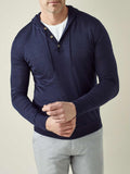 A model adjusting the ribbed cuff on his navy blue silk-cashmere hoodie, layered over a white t-shirt.