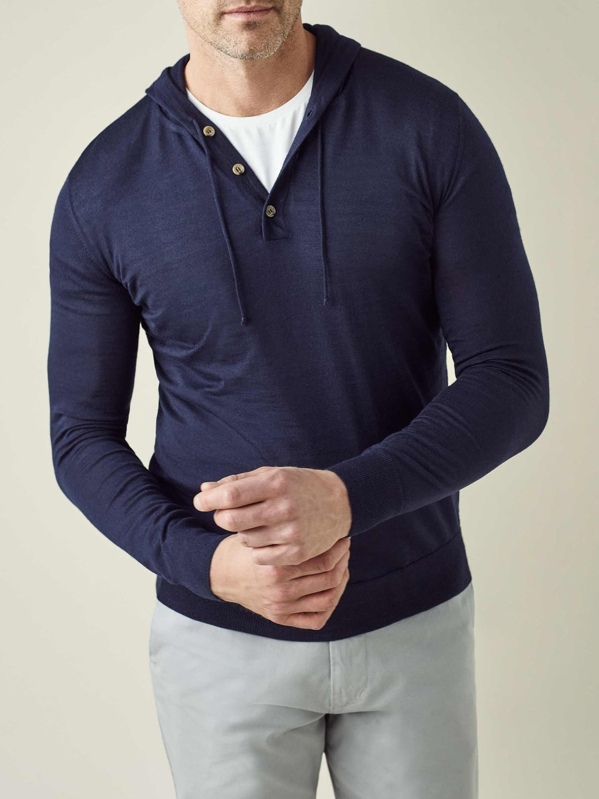 A model adjusting the ribbed cuff on his navy blue silk-cashmere hoodie, layered over a white t-shirt.