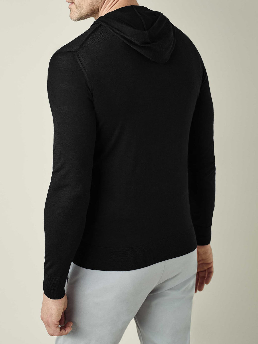 Rear view of a model wearing the Luca Faloni Black Silk-Cashmere Hoodie, showcasing its streamlined silhouette.