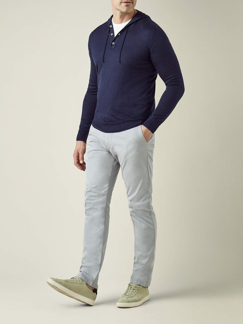 A model wears the Luca Faloni Silk-Cashmere Hoodie in Navy Blue with light grey trousers and light green sneakers.