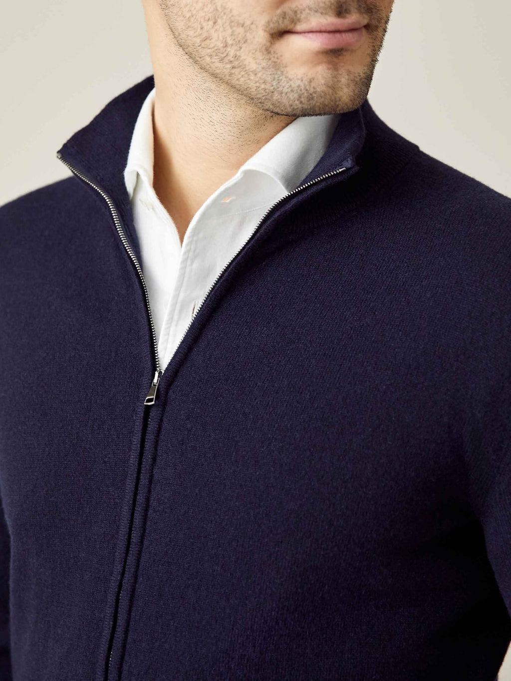 A man wears the Midnight Blue Cashmere Zip Cardigan half-zipped over a white collared shirt, highlighting the funnel collar.