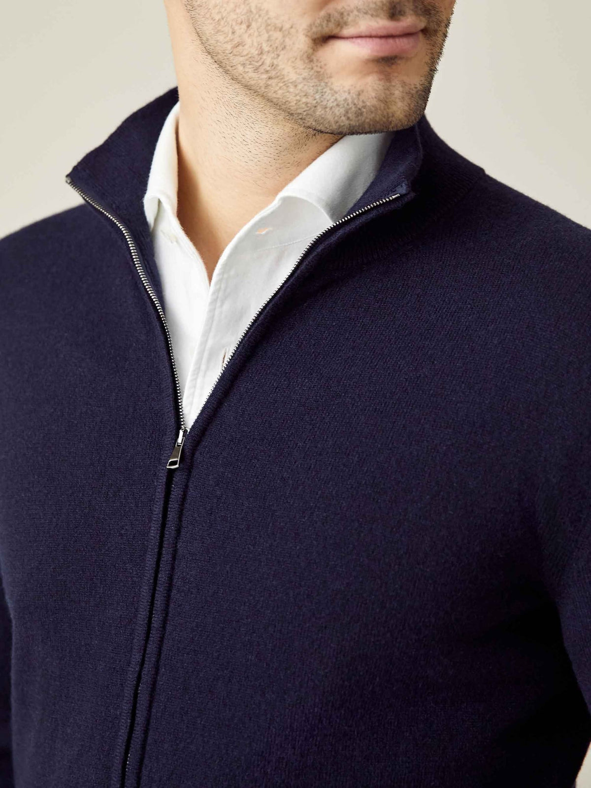 A man wears the Midnight Blue Cashmere Zip Cardigan half-zipped over a white collared shirt, highlighting the funnel collar.