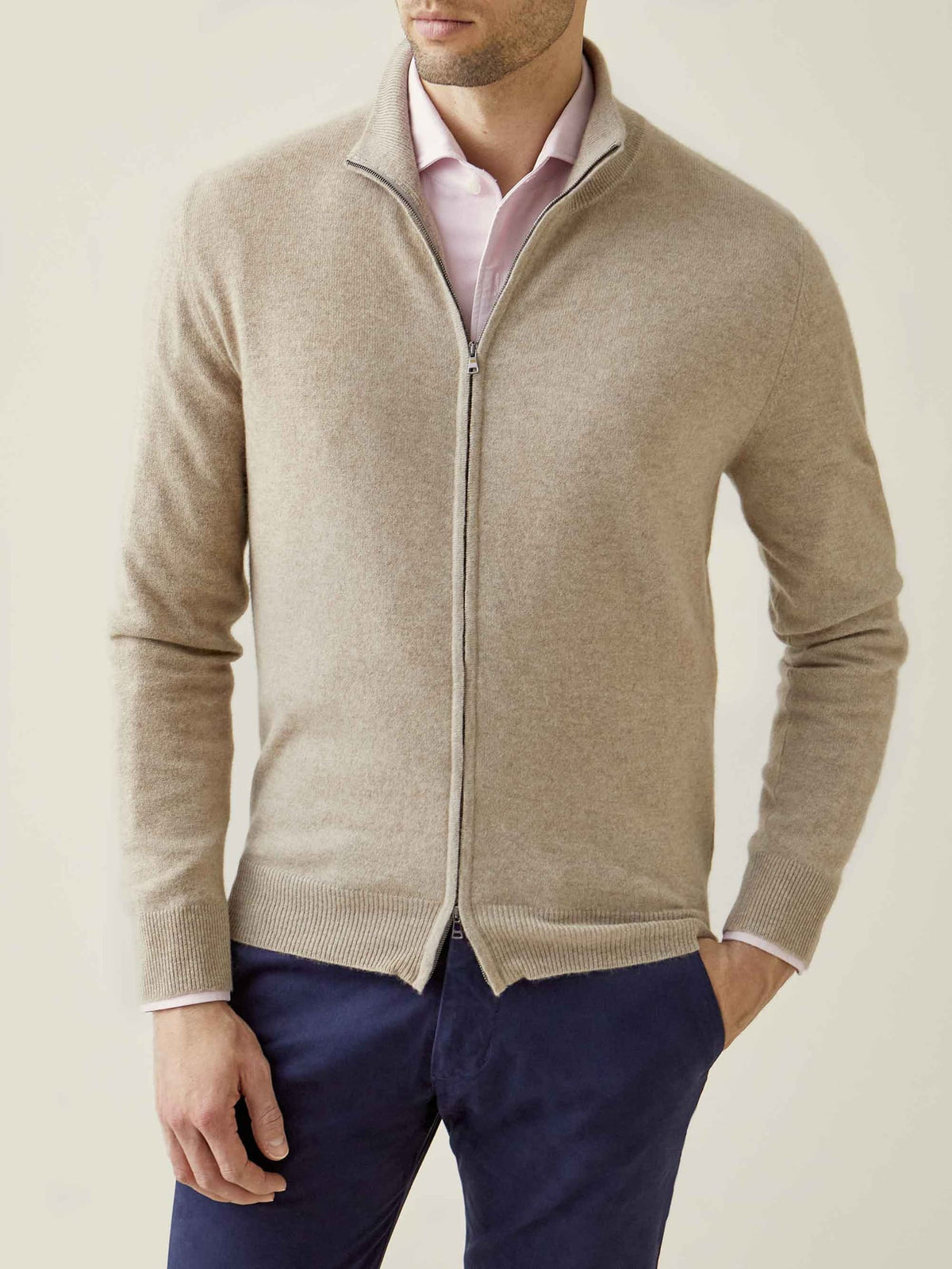 Model wears the Luca Faloni Camel Beige Cashmere Zip Cardigan over a pink shirt and navy trousers.