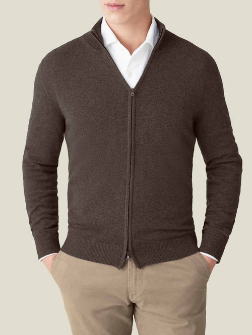 Front view of a man wearing a chocolate brown cashmere zip cardigan over a white shirt and beige trousers.