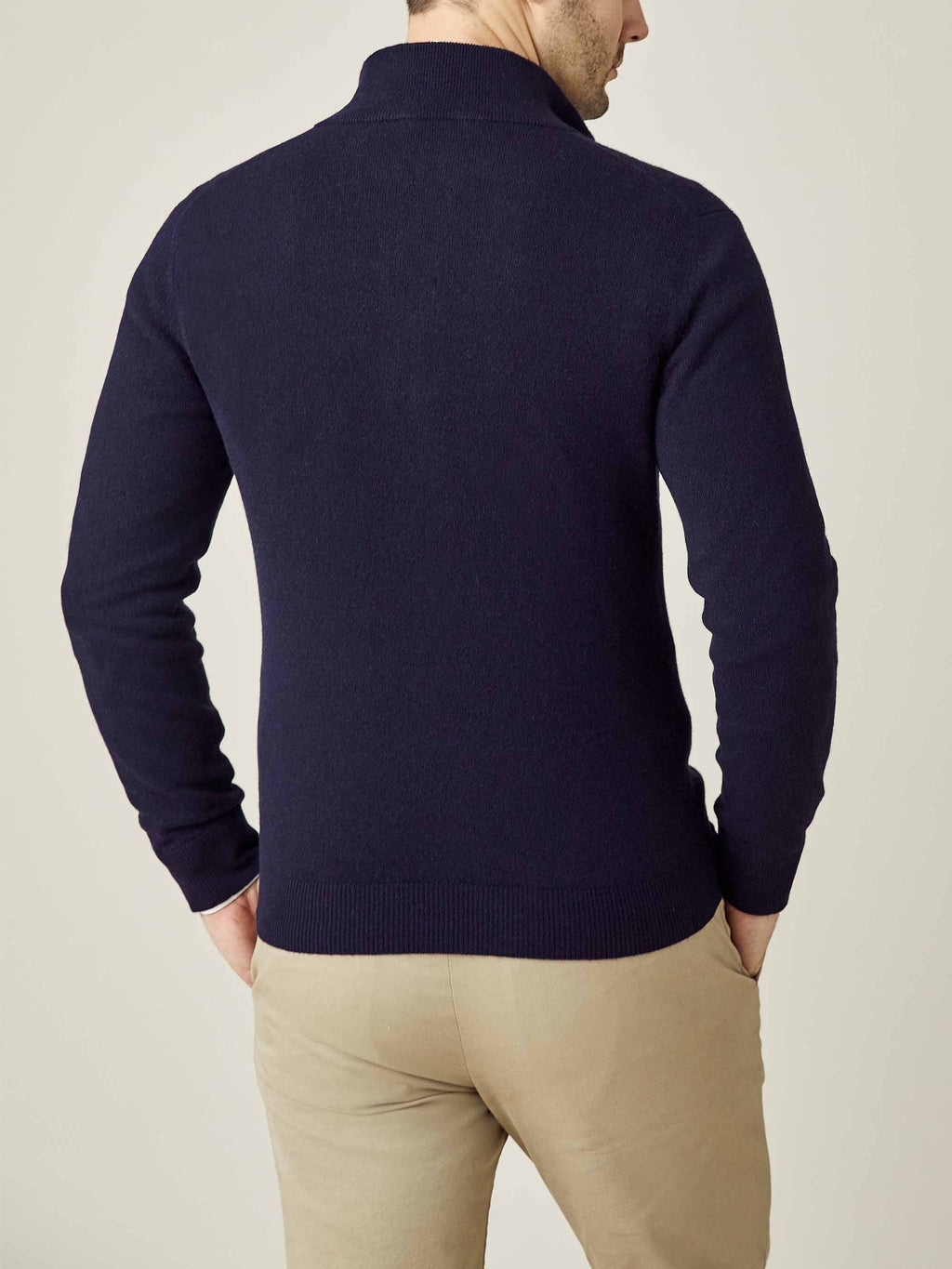 Back view of a model wearing the Midnight Blue Cashmere Zip Cardigan, paired with beige trousers.