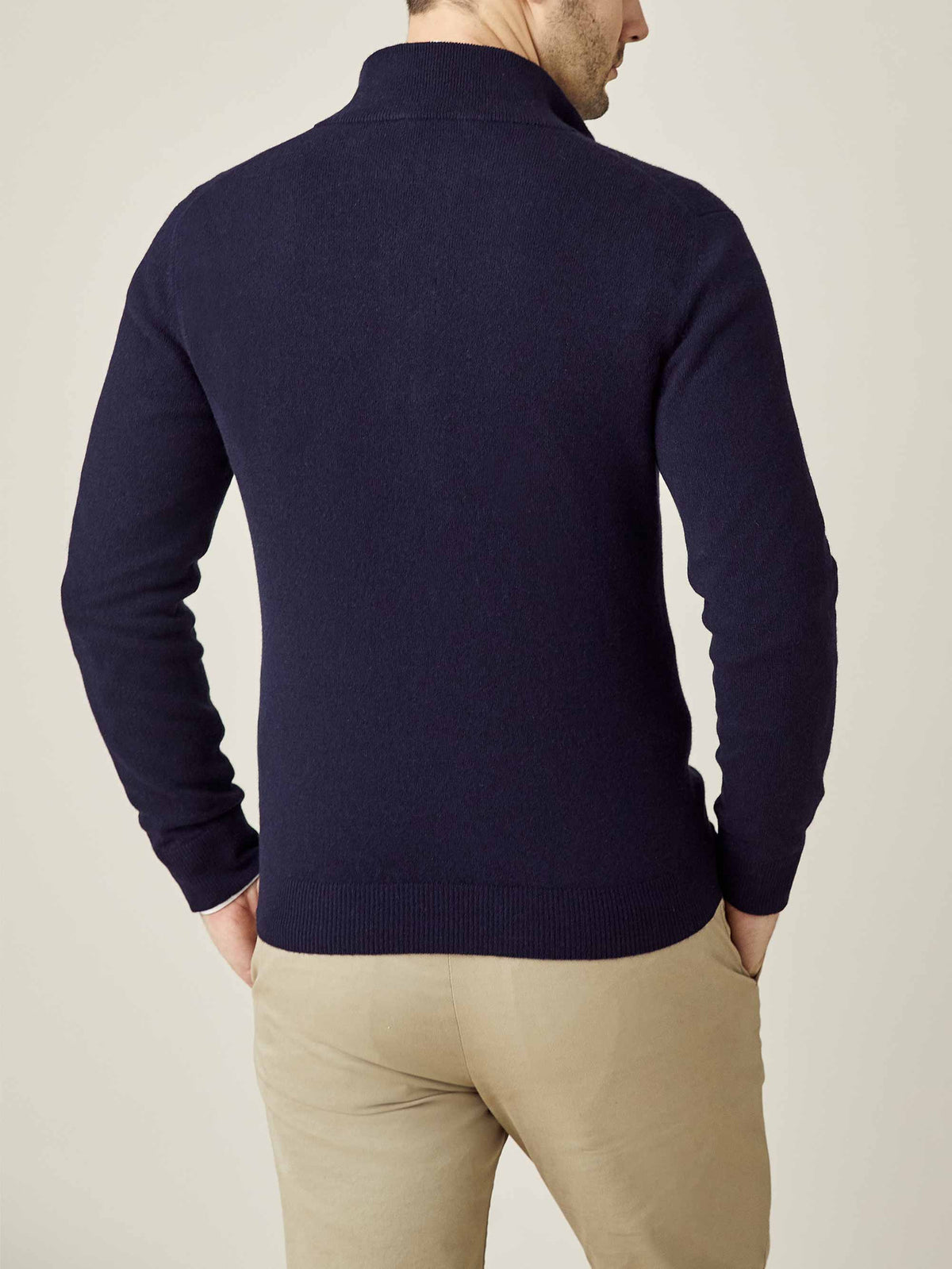 Back view of a model wearing the Midnight Blue Cashmere Zip Cardigan, paired with beige trousers.
