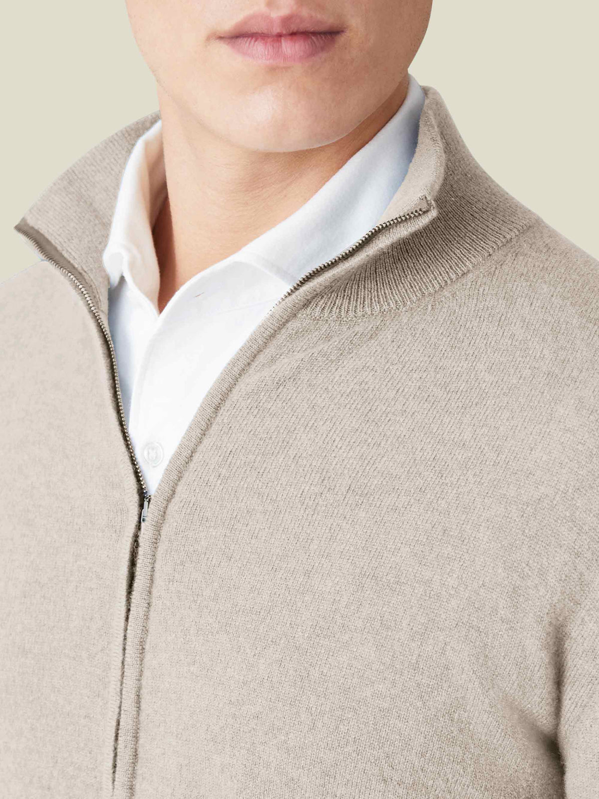 Close-up of a man wearing the Almond Cashmere Zip Cardigan over a white shirt, detailing the soft texture and ribbed collar.