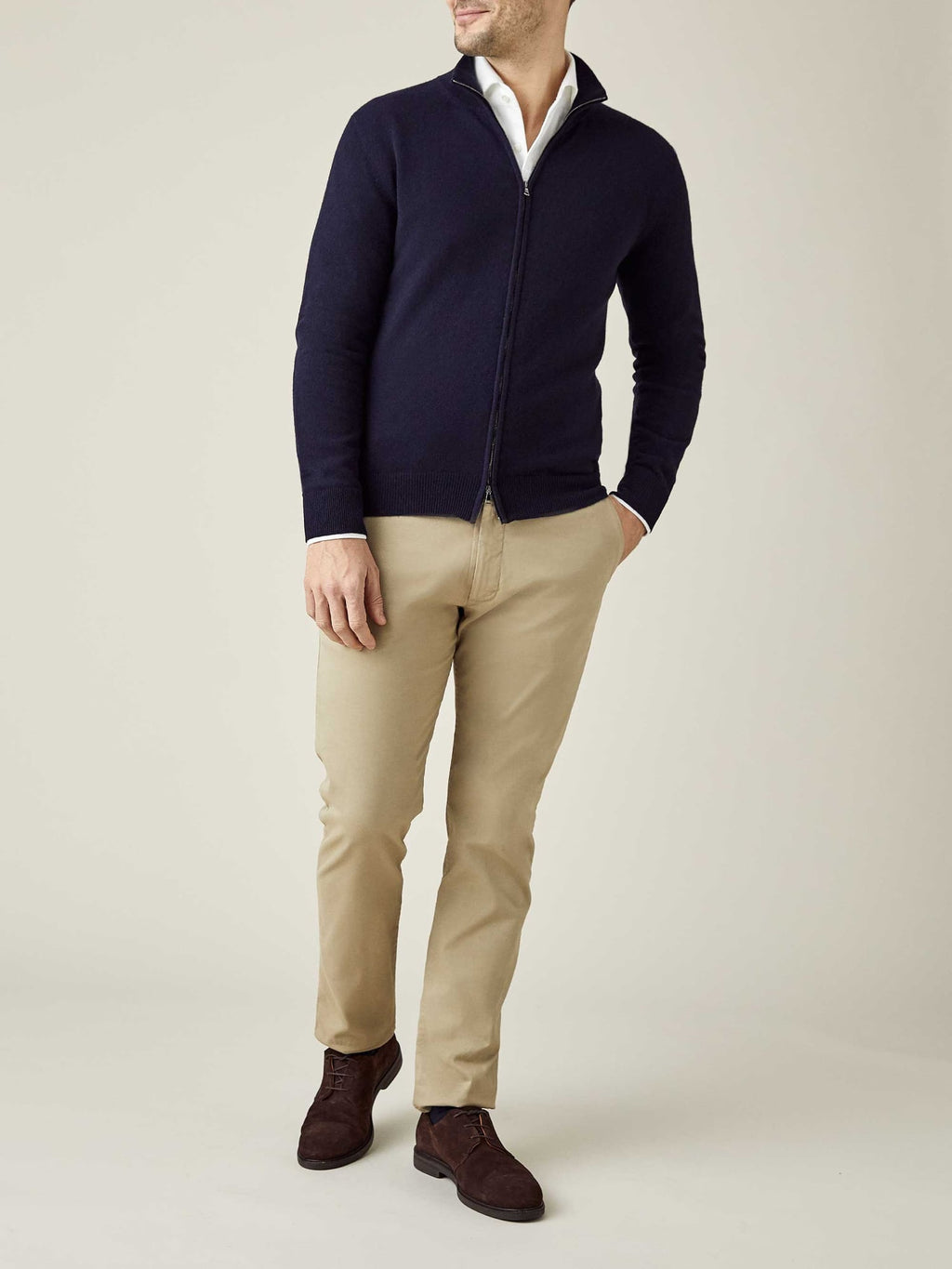 Styled shot of a model wearing the midnight blue cashmere zip cardigan with a white shirt and beige trousers.