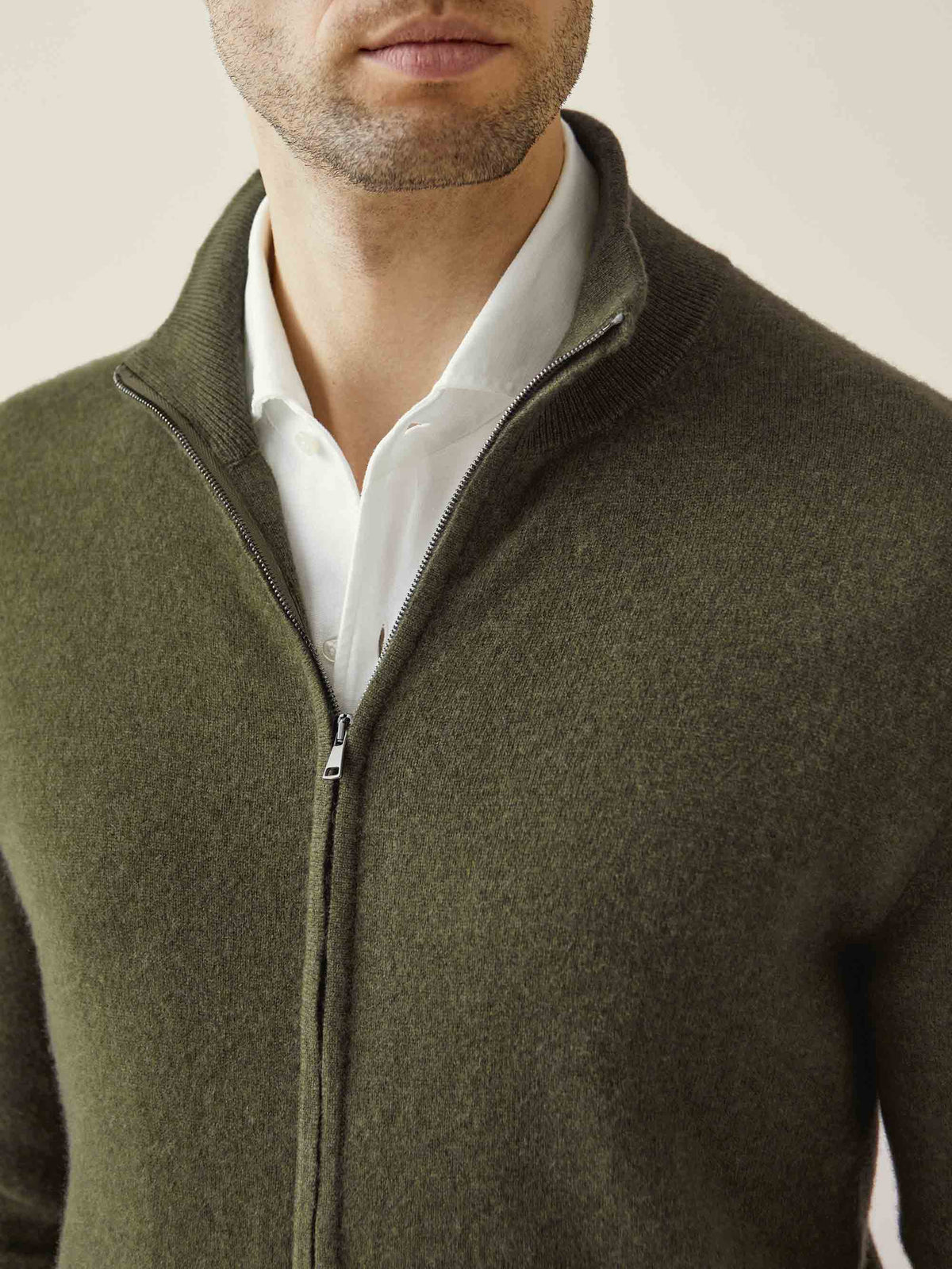 A close-up of a man wearing the Hunting Green Cashmere Zip Cardigan, showcasing its soft texture and ribbed funnel collar.