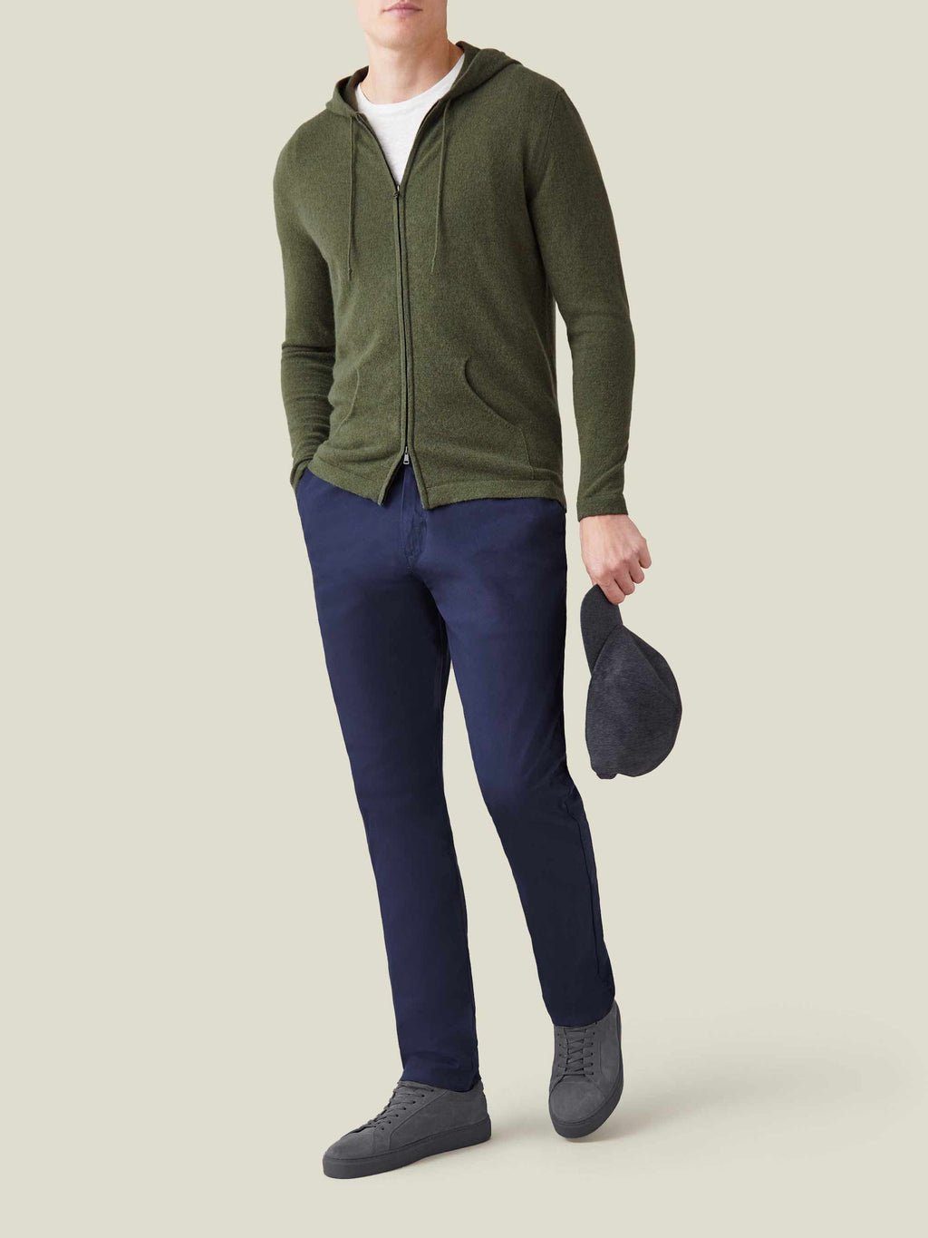 A man models the Luca Faloni hunting green cashmere zip hoodie open over a white tee, with navy chinos and grey sneakers.