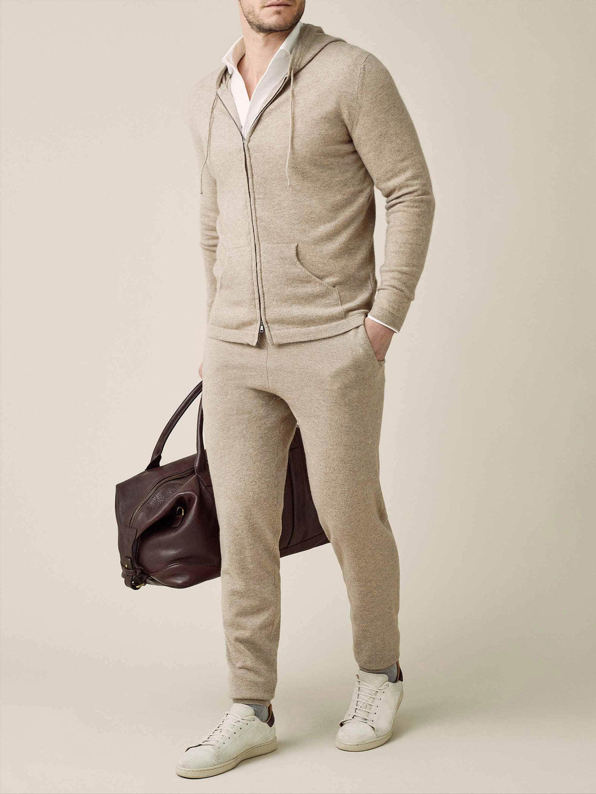 Model wears the Camel Beige Cashmere Zip Hoodie with matching joggers, white shirt, and sneakers, holding a leather bag.